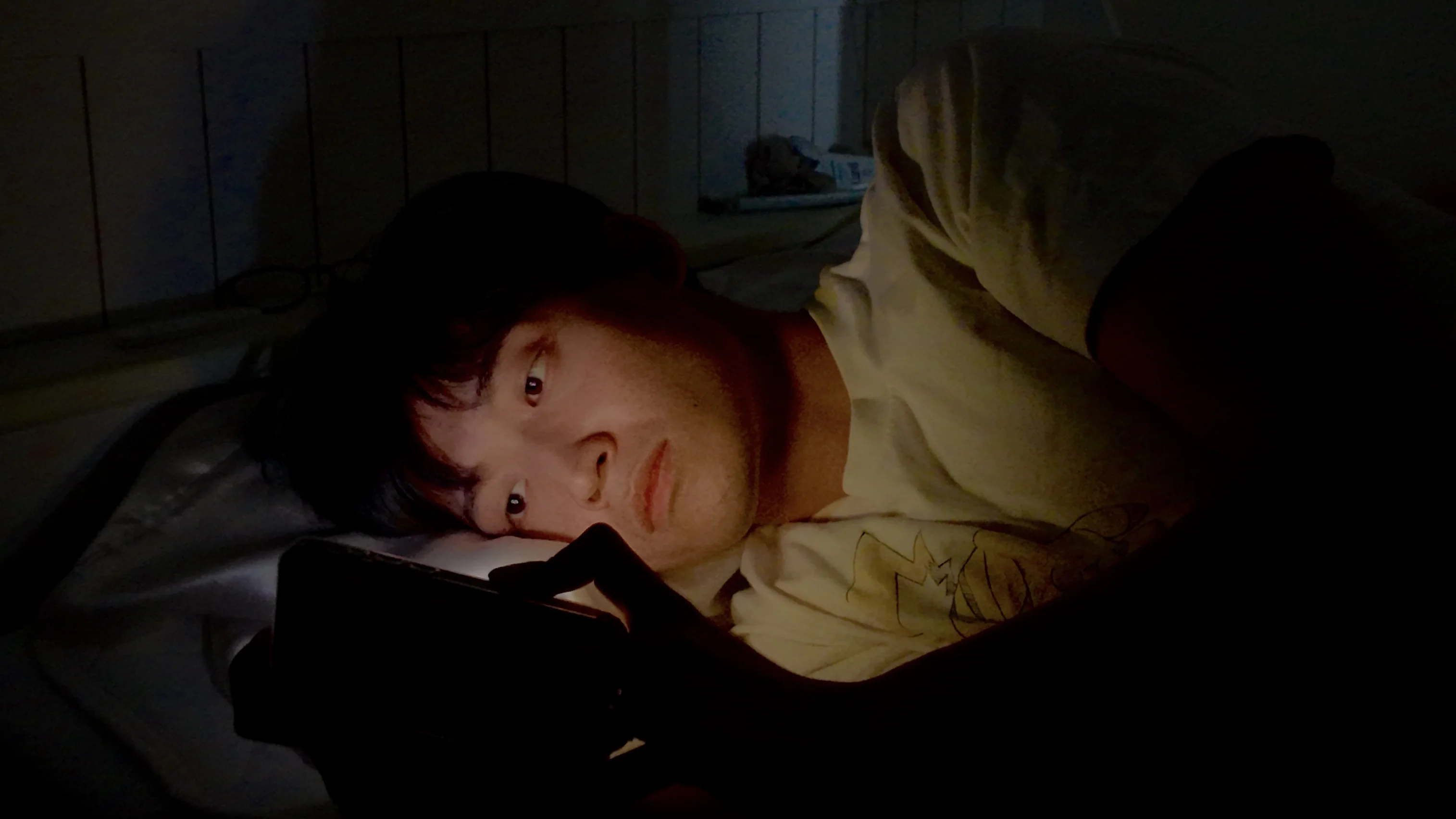 夜、暗い部屋でスマホの画面を見つめる人